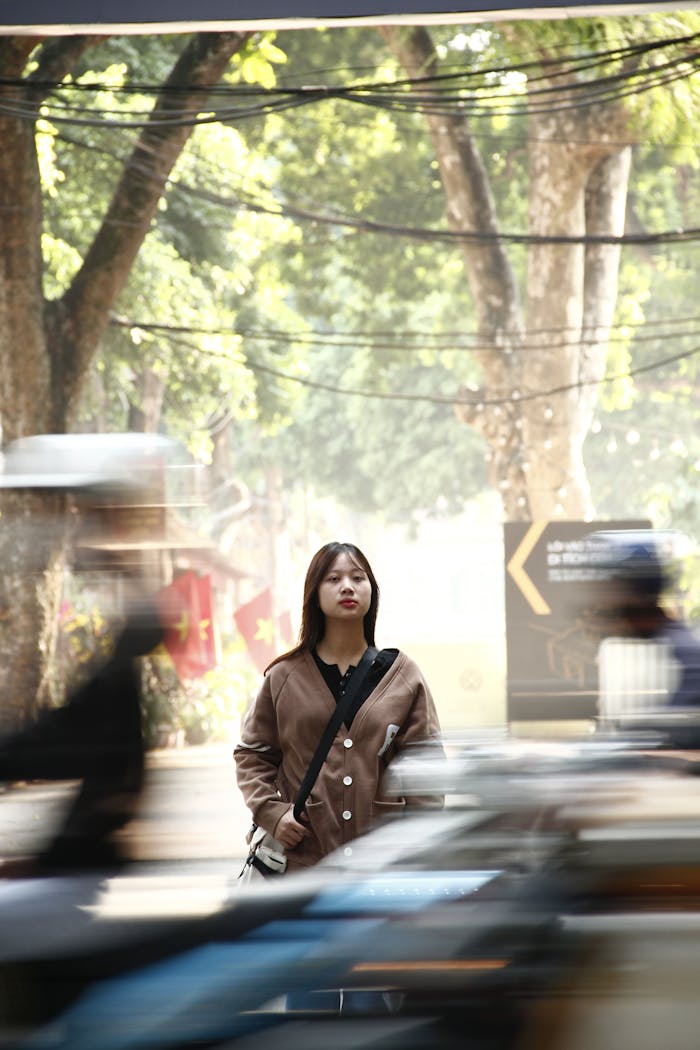 A Woman Standing on a Street among Moving Vehicles